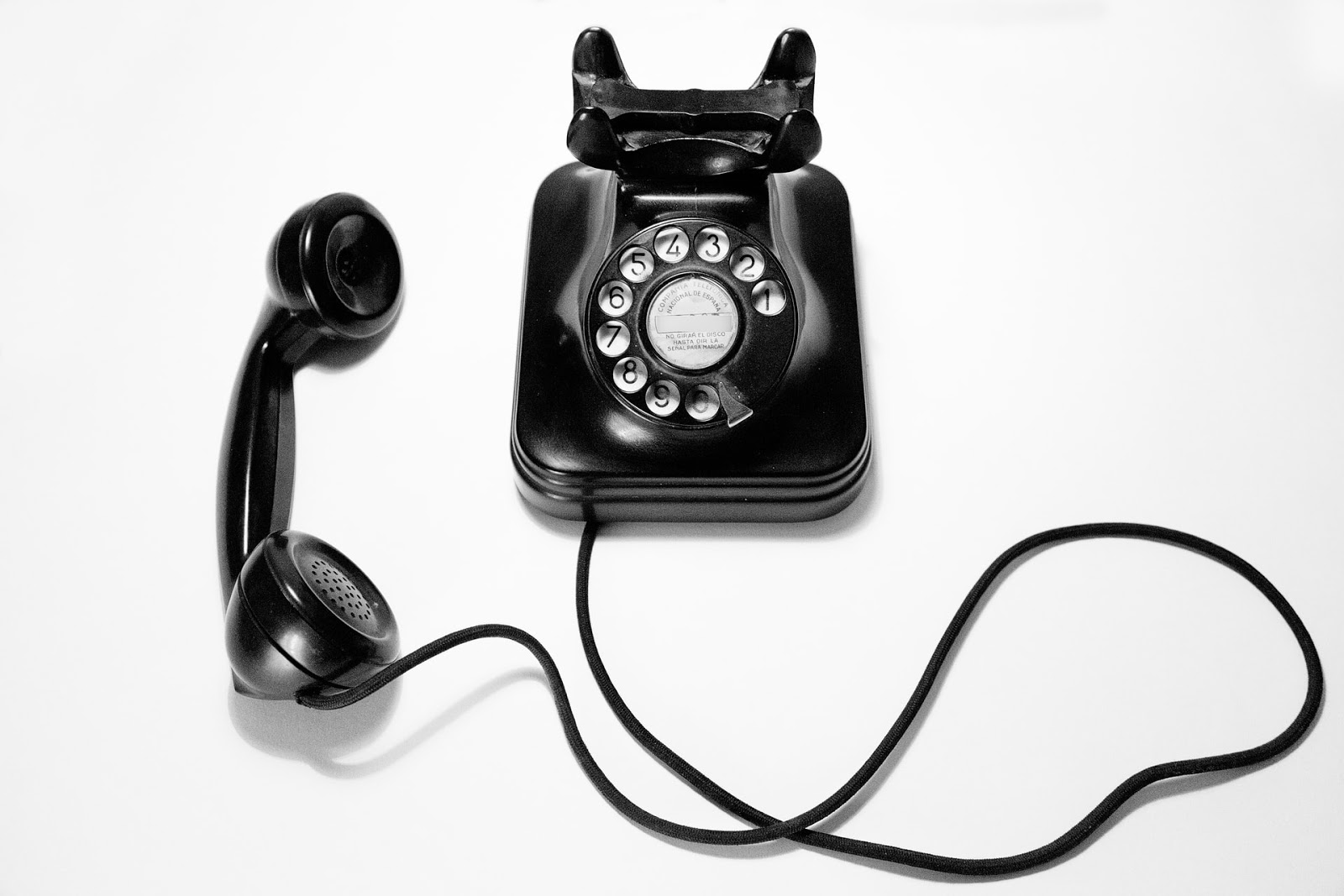 Black rotary telephone on the white surface