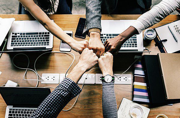 Team-fist-bumping-over-laptops Team fist bumping over laptops