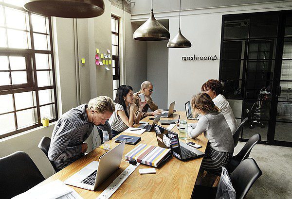 Team-sitting-behind-table-working Team sitting behind table working